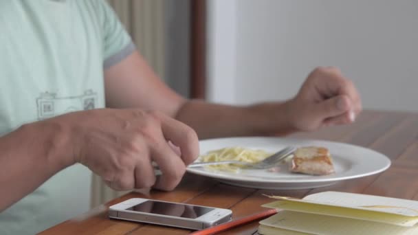 Jonge man met behulp van de telefoon terwijl het eten van ontbijt — Stockvideo