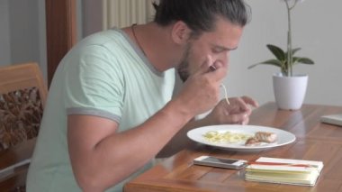 Genç bir adam spagetti ile bir orkinos biftek yiyor.