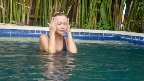 Щаслива молода жінка розслабляється біля розкішного басейну — стокове відео