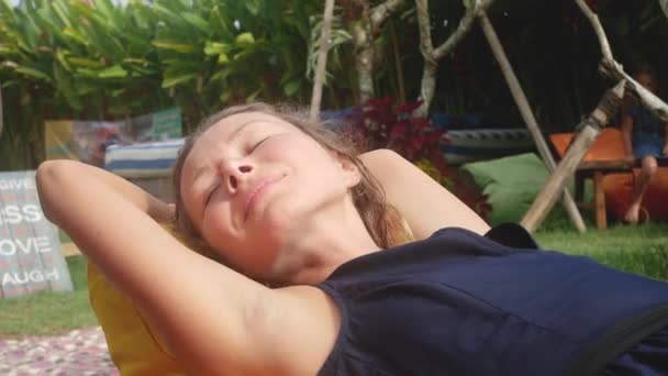Vrouw ontspant in een zak-stoel op een open plek met groen gras — Stockvideo