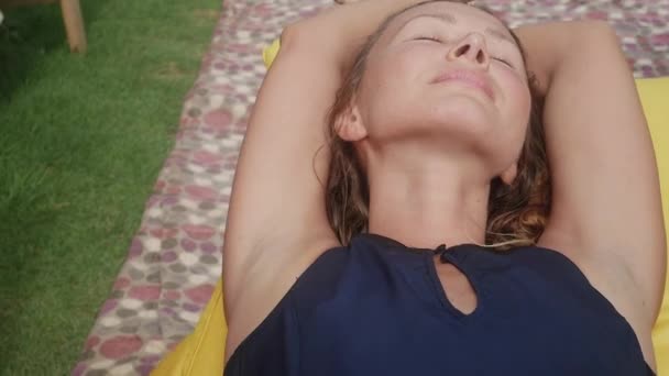 Mulher relaxa em uma bolsa-cadeira em uma clareira com grama verde — Vídeo de Stock