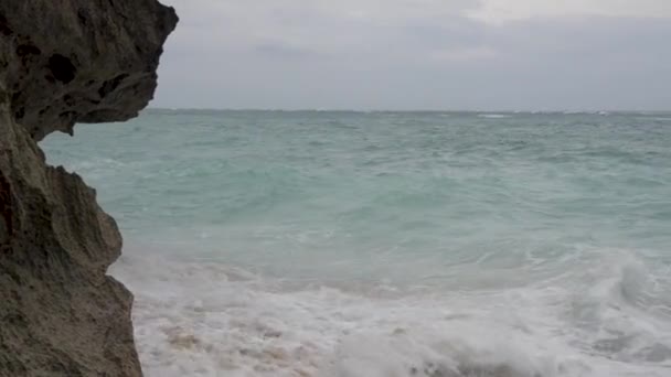 Golven crash tegen rotsen op een strand in Bali. — Stockvideo