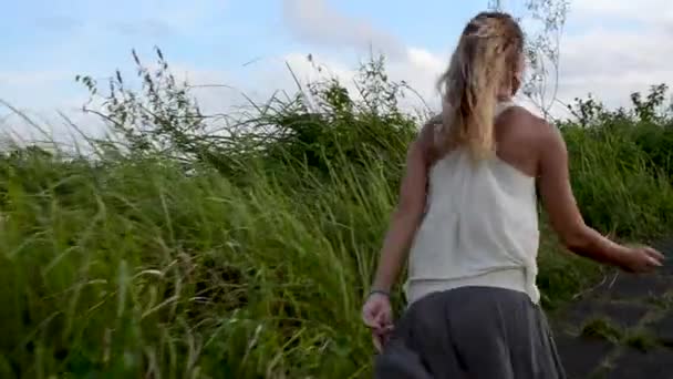 Junge schöne Frau, die bei Sonnenaufgang auf Reisfeldern spaziert — Stockvideo