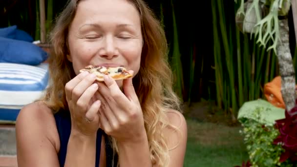 Hipster chica comiendo pizza y sonriendo a la cámara en el restaurante — Vídeos de Stock