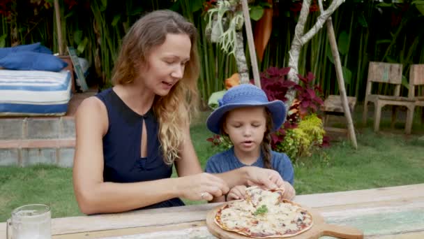 Gyermekek anyja pizzát eszik a strandon — Stock videók