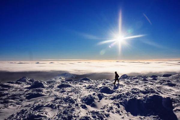 Lonely man in the mountains in winter above the clouds