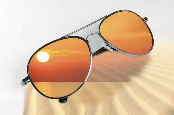Солнцезащитные очки, отражающие небо на закате — стоковое фото