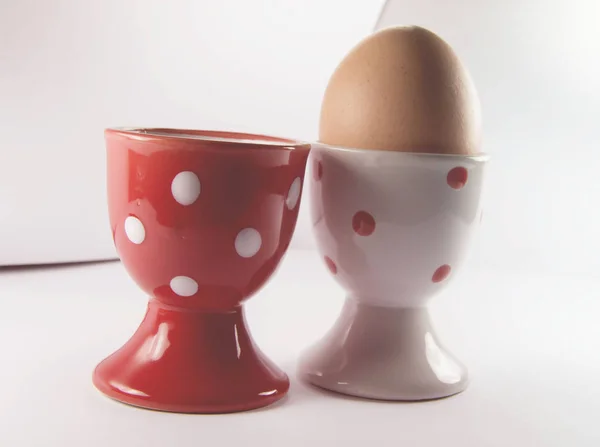 लाल अंडे कप के साथ सफेद अंडे कप में अंडे — स्टॉक फ़ोटो, इमेज