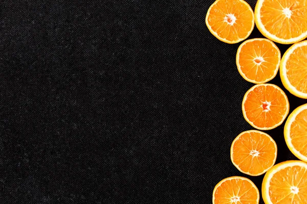 Yarım portakal ve mandalina ile kompozisyon bir siyah kontrplak arka plan kesmek.