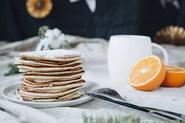 Akçaağaç syrop ve şeker tozu ile bir fincan sade kahve ve portakal tepesinde geleneksel Amerikan krep içeren kahvaltı sahnenin bir natürmort