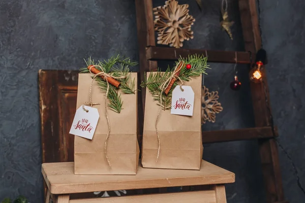 İki hediye Noel mahalline Paketli kraft kağıt ve küçük çam dalları ile dekore edilmiş ve bir tarçın sopa