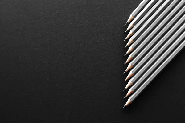 Onbir gri kalem çapraz olarak metin için bazı ücretsiz boş yer siyah bir zemin sağ tarafında yer
