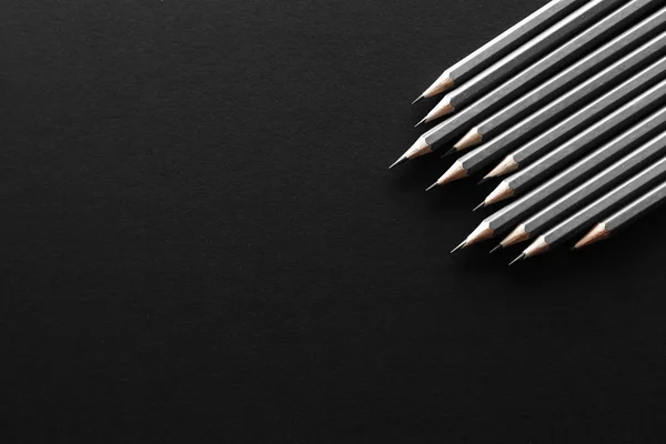 Onbir gri kalem çapraz olarak metin için bazı ücretsiz boş yer siyah bir zemin sağ tarafında yer