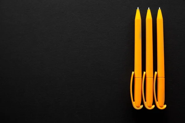 Dikey metin için bazı ücretsiz boş yer ile siyah bir zemin sağ tarafında yerleştirilmiş üç sarı kalemler