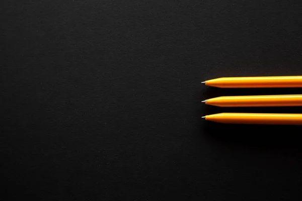 Bazı ücretsiz boş yer için metin ile siyah bir zemin sağ tarafında üç sarı kalemler yer