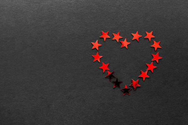 Küçük kırmızı yıldız yapılan bir kalp bir siyah mat zemin üzerinde metin için bazı ücretsiz boş yer yer