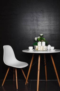 Beyaz bir sehpa beyaz bardak ve çay potu, beyaz mumlar, bazı yeşil çim ve çiçek ile. Beyaz bir sandalye eşlik etti. çatı tasarım