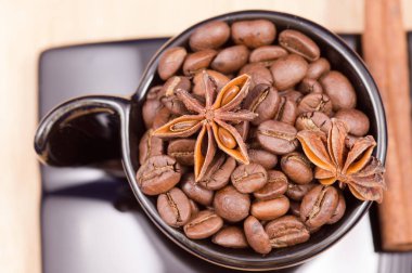 Kahve çekirdekleri, anason ve tarçın ahşap yüzey üzerinde siyah Kupası dolu