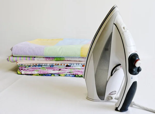 Modern iron and stack of ironed linen. Household chores.