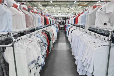 Beyaz ve açık renkli kadın gömlekleri bir elbise ve ayakkabı mağazasında askılara ve mankenlere asılı..