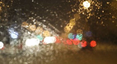 Bulanık şehir arkaplanı. Gece şehrindeki araba penceresinin manzarası. Bulanık bokeh ışıkları, sokak ışıkları ve araba farları..