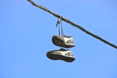 A pair of old sneakers on telephone wires in the city. clipart