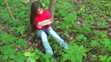 Güzel genç kız tablet bilgisayar ile Park cephede oturur. 