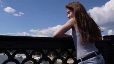Güzel genç kız saç rüzgarda ile köprü mavi gökyüzü arka plan üzerinde portresi
