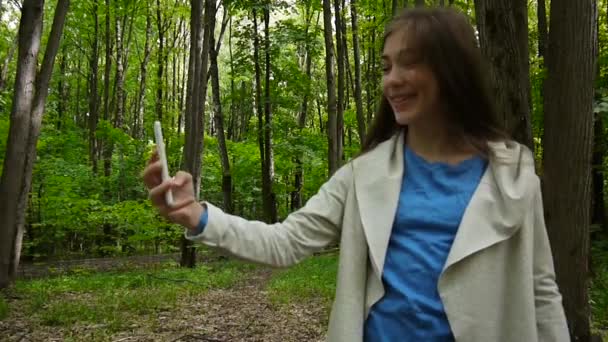 夏天, 女孩在公园拍摄自拍的照片智能手机。姿势和微笑。视频拍摄静态摄像机. — 图库视频影像