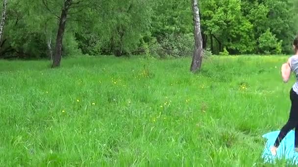 Jonge mooie tiener meisje het beoefenen van fitness uitoefenen buiten in park in zomerdag. HD verkeer camera panorama met steadicam. — Stockvideo