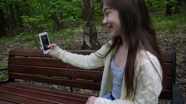 女孩采取自拍相片智能手机, loseup 采取在公园在夏天。姿势和微笑。视频拍摄静态摄像机. — 图库视频影像