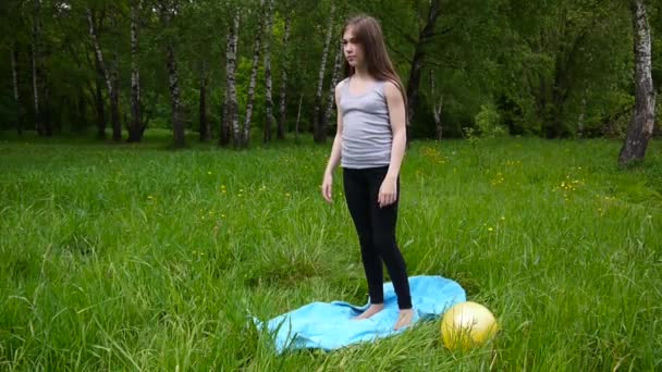 Jonge mooie tiener meisje het beoefenen van fitness uitoefenen buiten in park in zomerdag. HD schieten statische camera. — Stockvideo