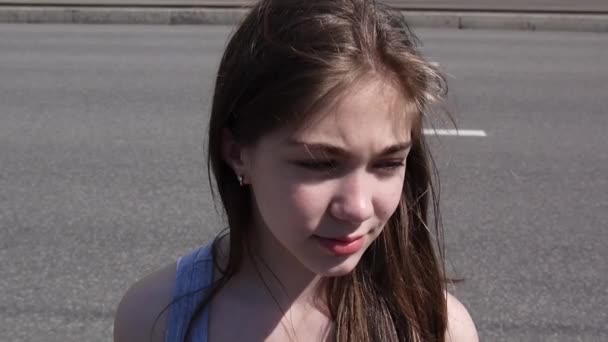 Closeup of cute caucasian teen girl on a city background. Looks into the distance. Static camera. — Stock Video