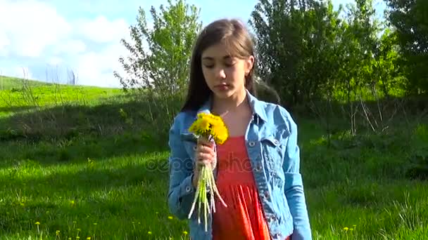 Portret van tiener meisje met gele paardenbloemen bloemen in het park — Stockvideo