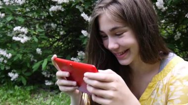 Güzel genç kız tablet bilgisayar ile Park cephede oturur. Statik kamera film.