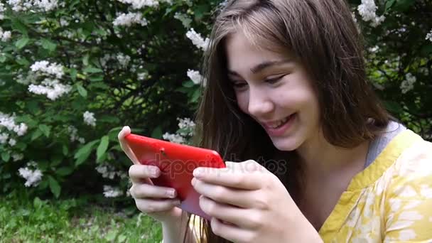 Hermosa chica adolescente con tableta se sienta en la hierba en el parque. Película de cámara estática . — Vídeos de Stock