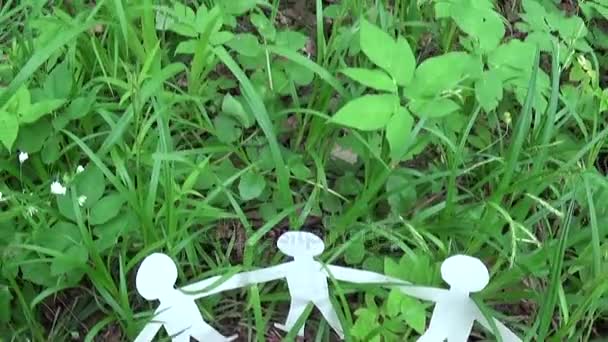 Concept of person and environment. Human figures made of paper on grass. Panorama slow motion camera from peoples figures to top of trees using Steadicam. — Stock Video