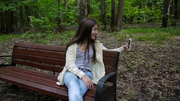 Tjej tar selfie foto smartphone, loseup tar på park i sommar. Poserar och leende. Video skytte statisk kamera. — Stockvideo