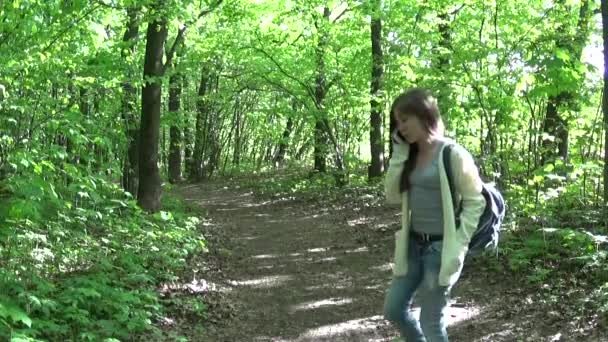 Young attractive girl speak using phone walking on the park. HD video footage panorama with steadicam. — Stock Video