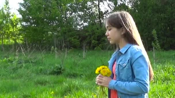 Portrait of teenager girl with yellow dandelions flowers in the park — Stock Video