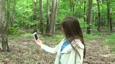 Selfie fotoğraf smartphone Parkı'nda yaz aylarında alarak kız. Poz ve gülümseyerek. Video çekim hareket kamera.