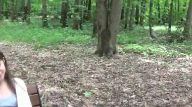 Genç çekici kız bankta telefona konuş. Yaz park. Gülümse. HD Video çekim hareket kamera steadicam ile.