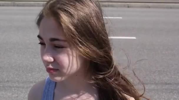 Close-up van schattige Kaukasische tiener meisje op de achtergrond van een stad. Ziet er in de verte. Statische camera. — Stockvideo
