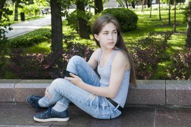 Genç çekici kız bankta telefon kullanın. Yaz park. Fotoğraf