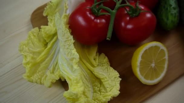 Uborka, kínai saláta, paradicsom, citrom, hagyma. Zöldség vágódeszka, videó, forgatás — Stock videók