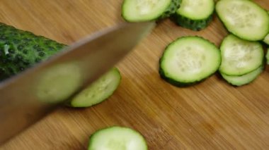 Taze yeşil salatalık bir ahşap tahta üzerinde kesme. Cook sebze bir bıçak ile kesmek. İkiye keser.