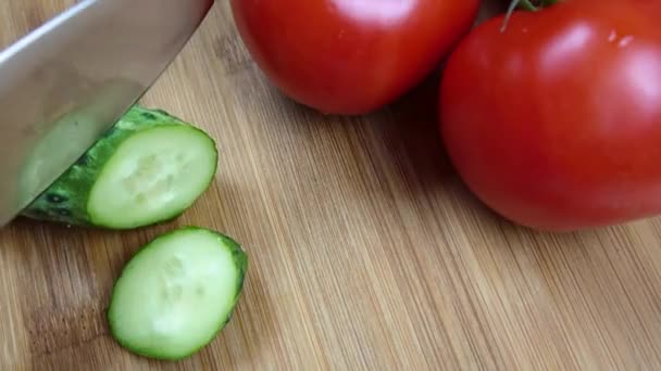 Taze yeşil salatalık bir ahşap tahta üzerinde kesme. Cook sebze bir bıçak ile kesmek. İkiye keser. — Stok video