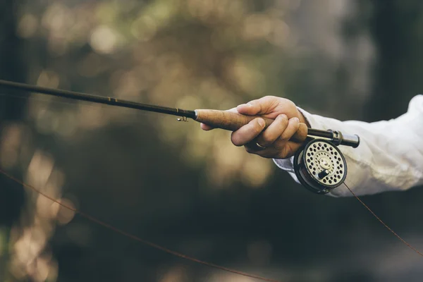 Caña de pescar con mosca en mano de pescador. — Foto de Stock