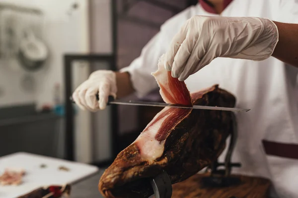 Pretty butchery woman cutting ham. — Stock Photo, Image