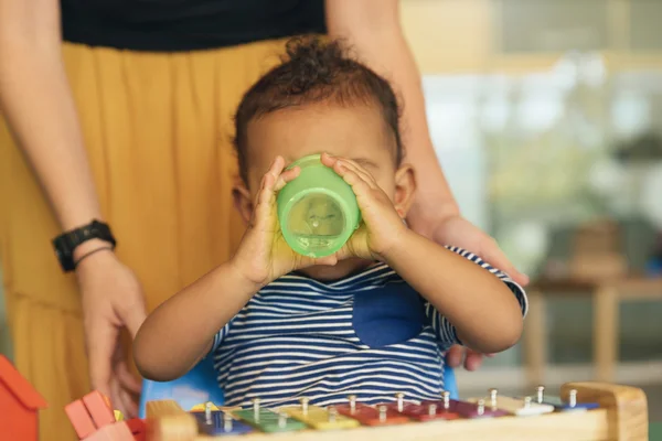 Glückliches Baby trinkt Wasser und spielt. — Stockfoto